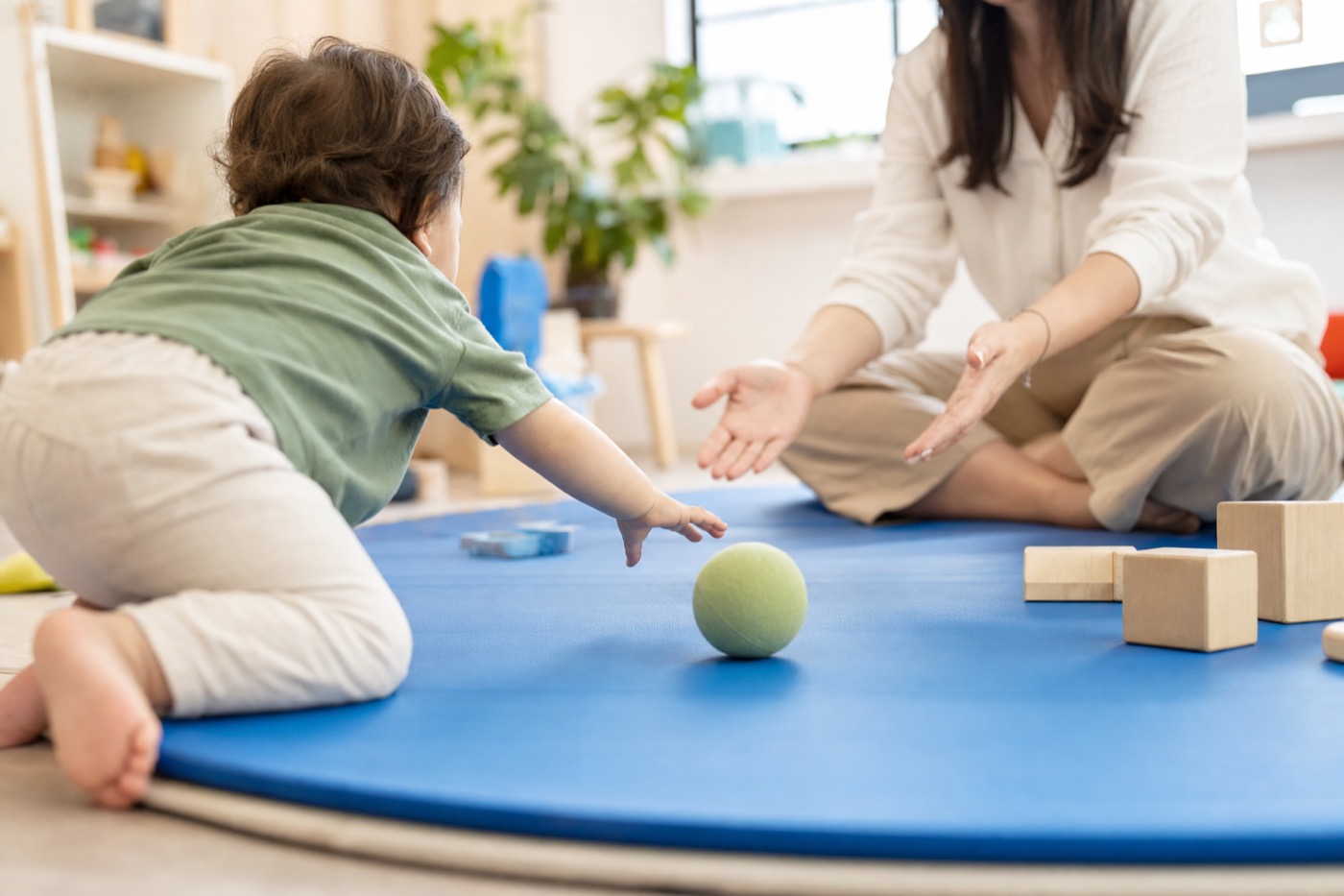 A young child practicing movement and play with a therapist in a bright therapy room.