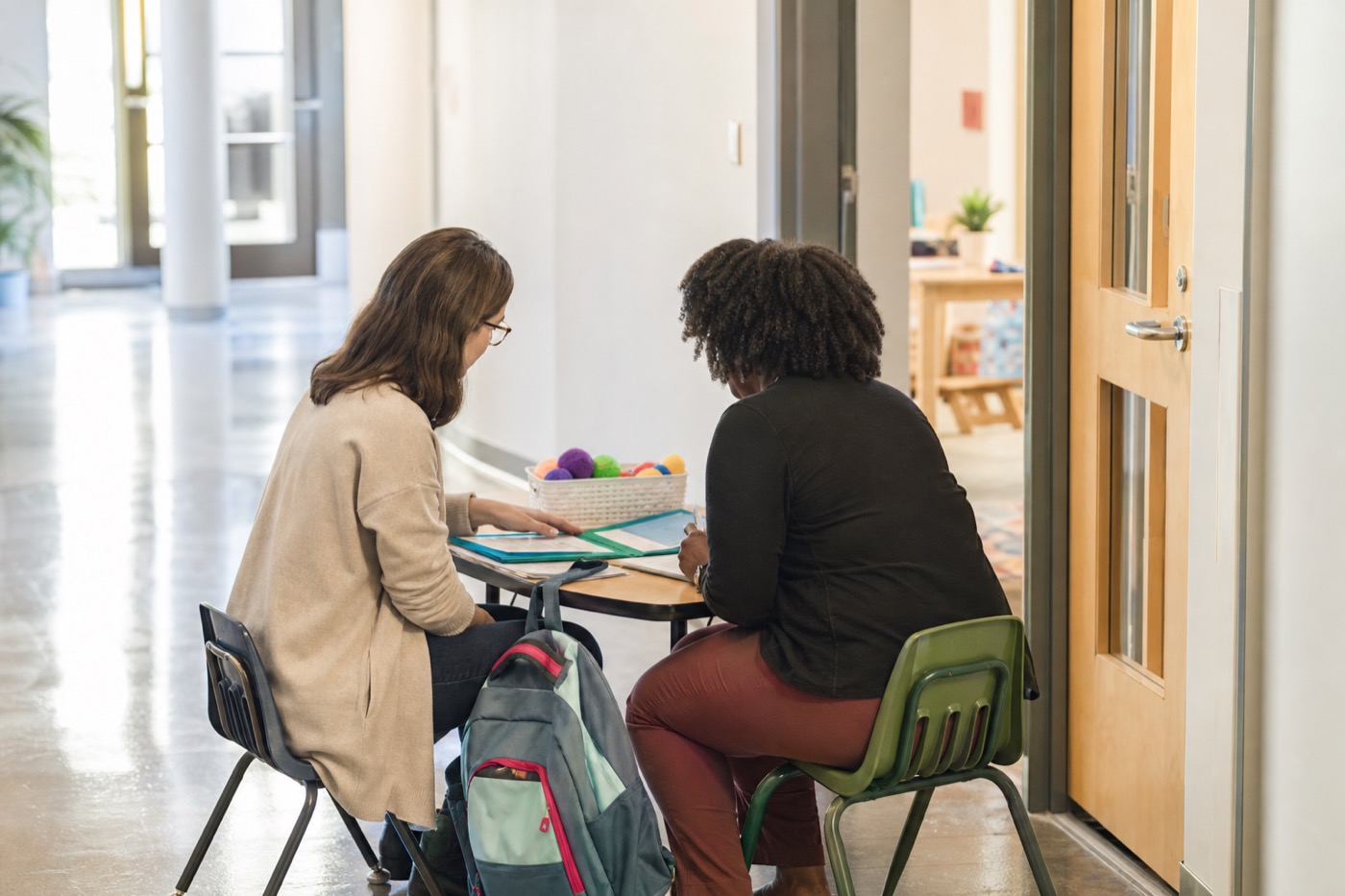 A school collaboration moment at a small table near a classroom doorway.
